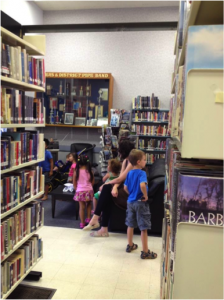 Photo of children browsing Prairie Crocus Library bookshelves with a parent